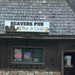 Beavers Pub Bar  Grill sign on a rustic wooden building with a small window beneath the sign