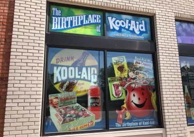 Birthplace of KoolAid Window Display Nebraska Directory Window display reading The Birthplace of Kool Aid Hastings Nebraska with vintage Kool Aid packaging