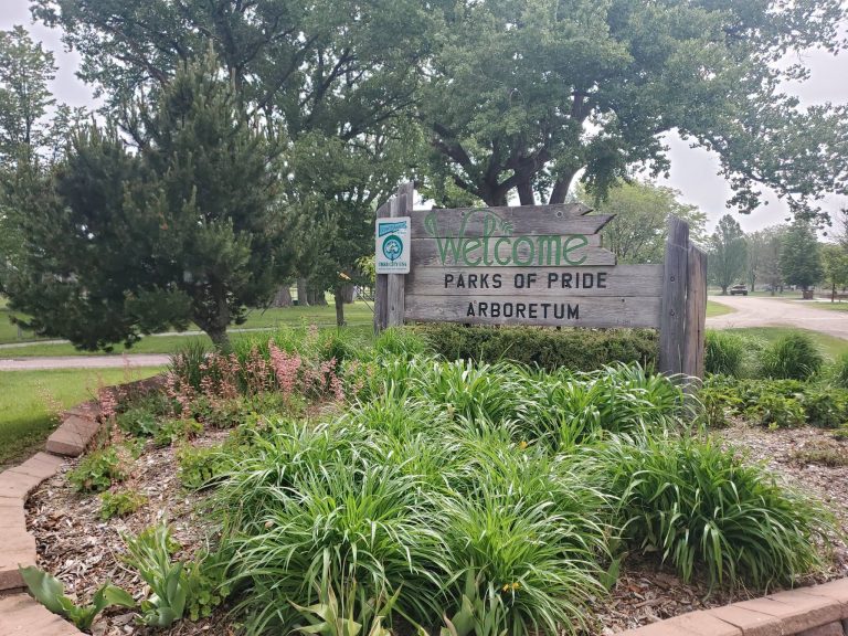 Welcome sign and lilies at the Parks of Pride Arboretum in Battle Creek
